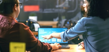 A man and women looking at laptop and discussing work