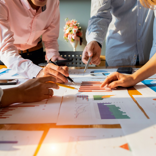 Colleagues discussing about various charts that are printed on paper
