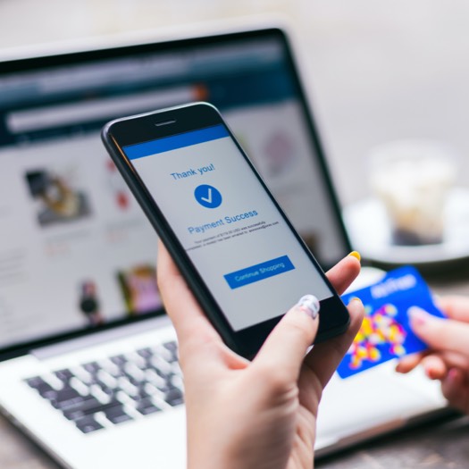 someone completed a payment on phone for purchase from website opened on laptop in background