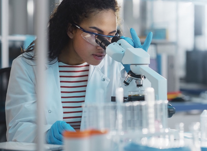 Woman in lab coat looking through microscope