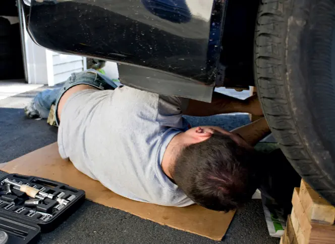 Man replacing autopart from underneath the car