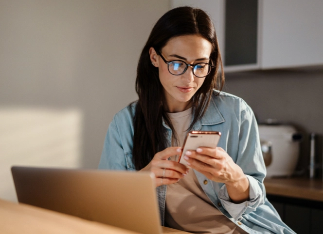 A woman reading something on her phone in her kitchen