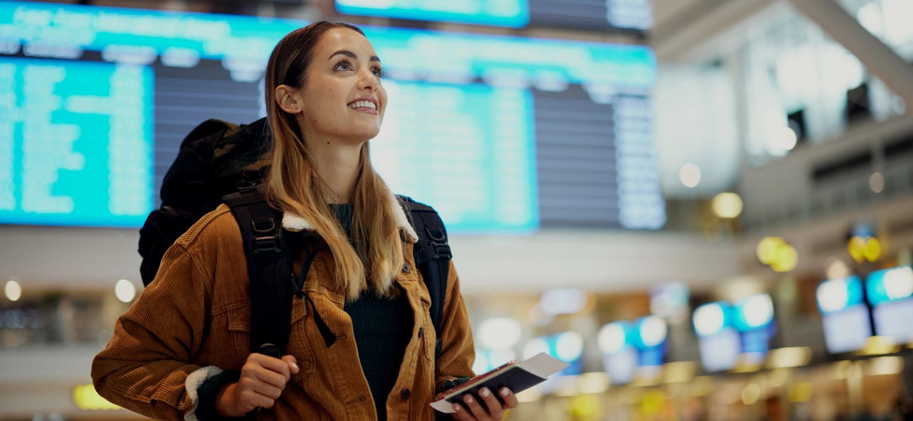 Woman looking happy seeing travel schedule at airport