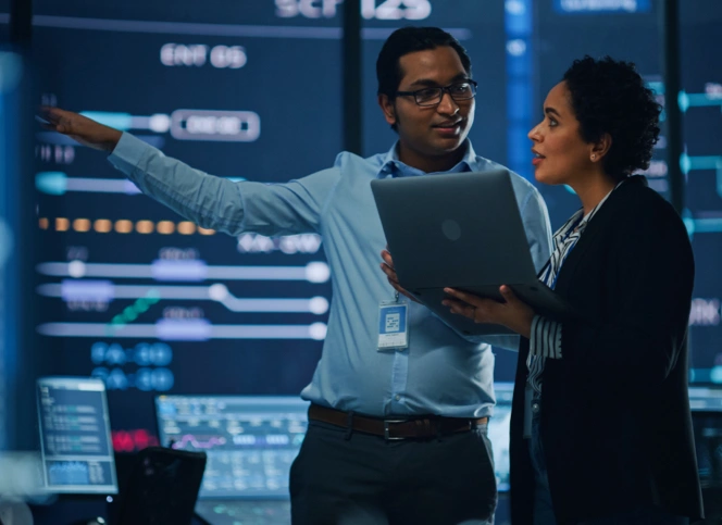 A man and a woman discussing a meeting room while staring at the projector screen.